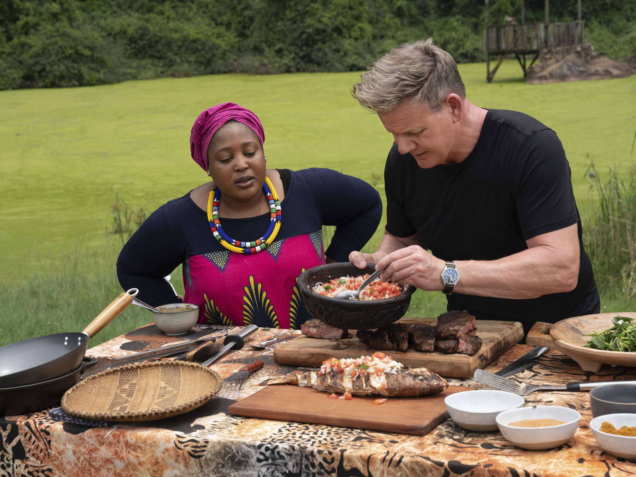 Chef Zola Nene (L) observes as Gordon Ramsay tops grilled Snapper with ushatini, a combination... [Photo of the day - September 2020]