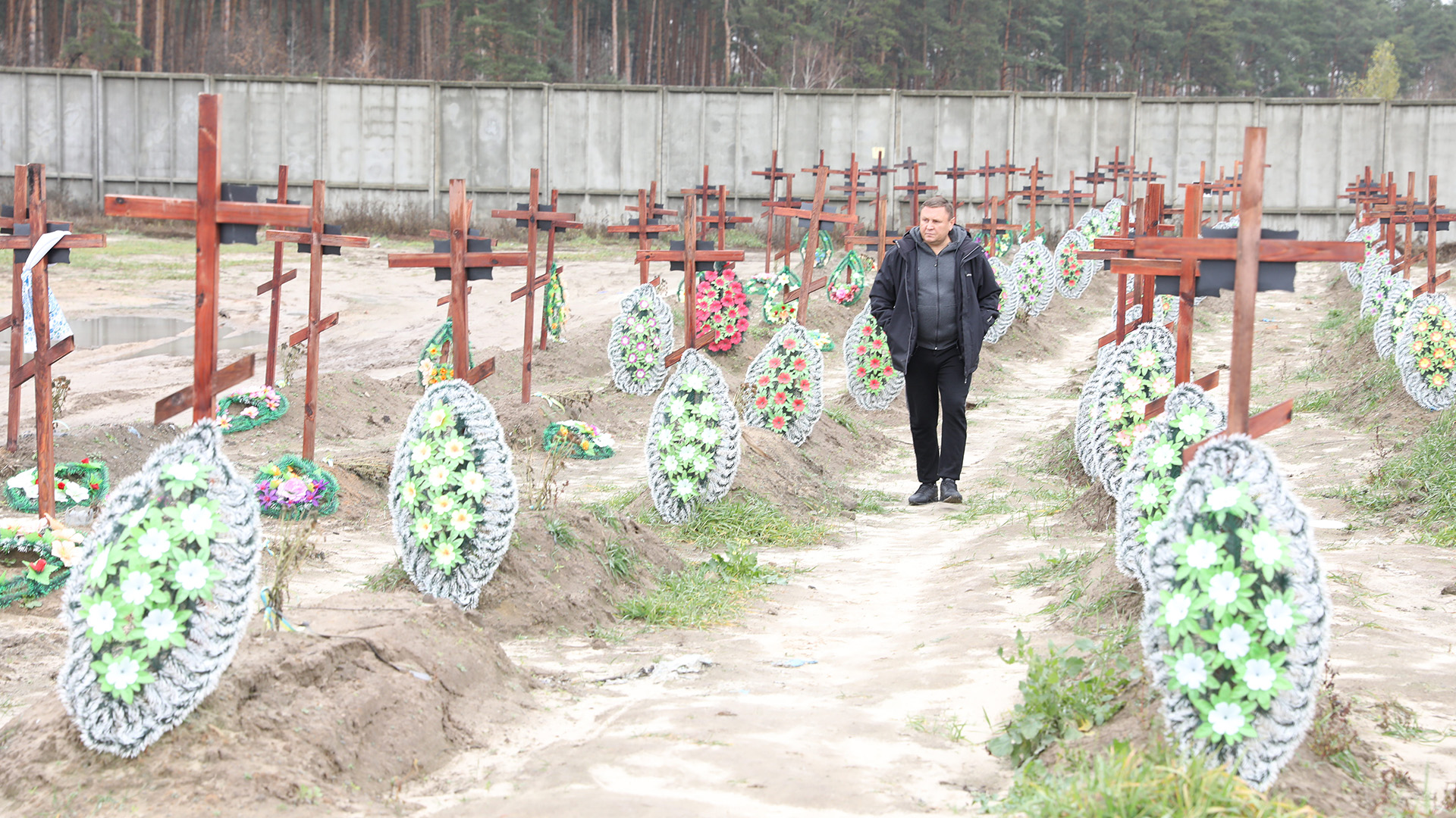 Local funeral director Serhiy Kaplychnyi walks alongside the makeshift graves of Bucha's dead,... [Photo of the day - February 2023]