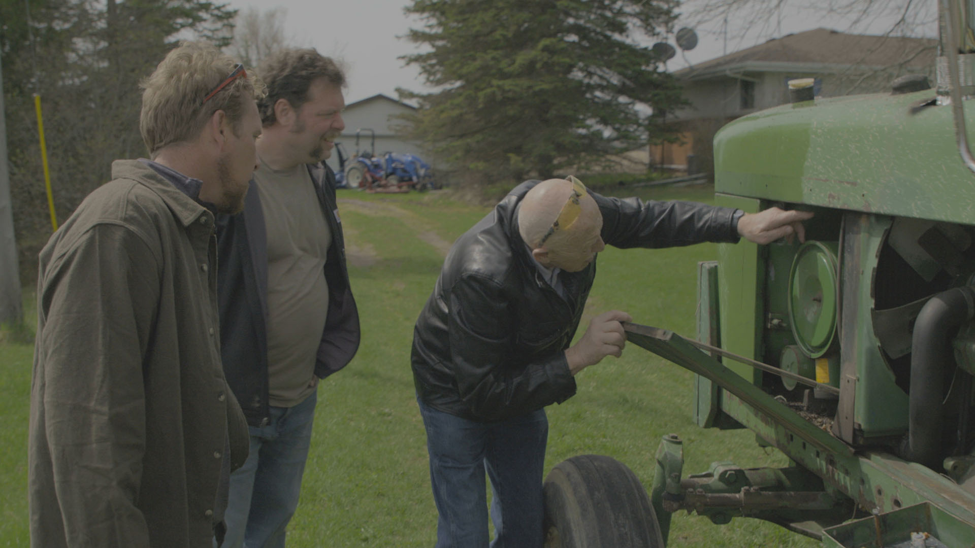 Ben Reinhold, Charles Pol, and Dr. Jan Pol inspecting their green tractor at the Pol family's... [Photo of the day - January 2024]