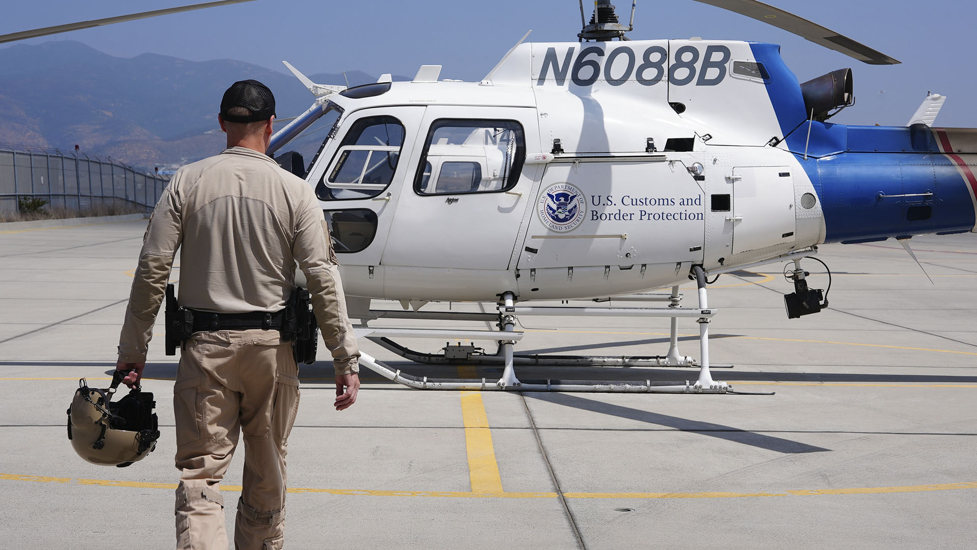 Air Enforcement Agent Murray is holding his helmet as he walks across a tarmac to a CBP air... [Photo of the day - September 2024]