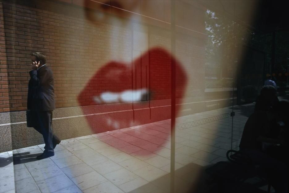 A reflected pair of luscious lips from a billboard yields the image of a passerby chatting on a... [Photo of the day - March 2011]