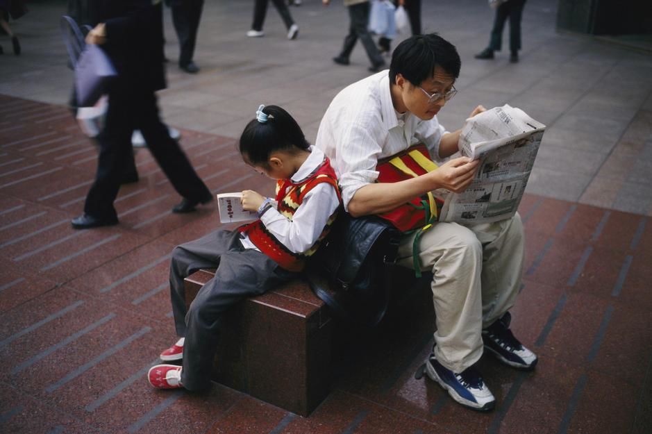 A man and his daughter lean against each other reading on Nanjing Lu, Shanghai. [Photo of the day - April 2011]